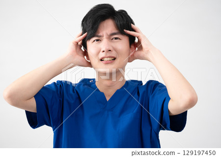 A young man wearing medical scrubs 129197450