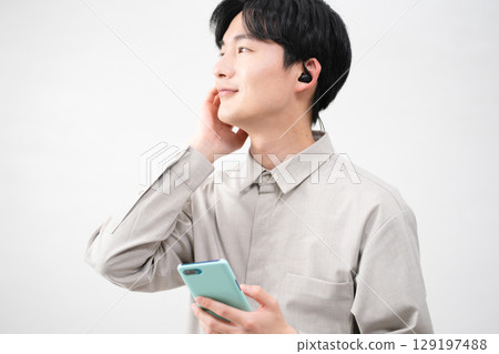 Young man listening to music with wired earphones Young man listening to music with wired earphones 129197488
