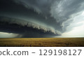 A massive supercell thunderstorm forms over a golden wheat field 129198127