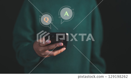 Young woman using a smartphone with virtual Q&A speech bubbles, representing online communication, chatbot AI systems, or customer support interaction. 129198262