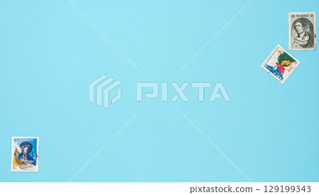 Postage stamps arranged diagonally on a pastel blue background 129199343