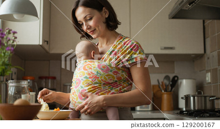 Mother caring for baby while cooking in a cozy kitchen Mother caring for baby while cooking in a cozy kitchen 129200167