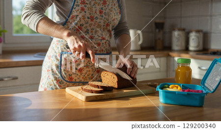 Woman cutting bread in a cozy kitchen 129200340