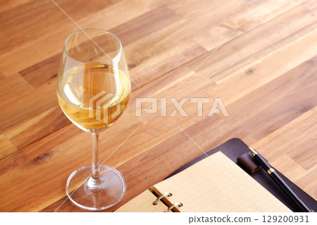 Image of a person writing a diary in a ring-type system organizer while drinking white wine Image of a person writing a diary in a ring-type system organizer while drinking white wine 129200931