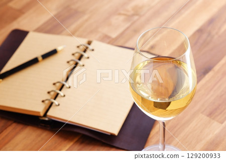 一個人一邊喝著白酒,一邊在環形記事本上寫日記 一個人一邊喝著白酒,一邊在環形記事本上寫日記 129200933