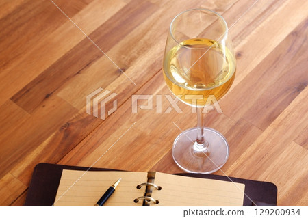 Image of a person writing a diary in a ring-type system organizer while drinking white wine Image of a person writing a diary in a ring-type system organizer while drinking white wine 129200934