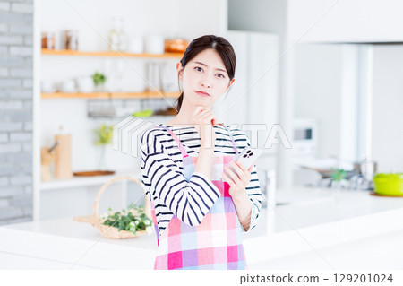 一位家庭主婦正在用智慧型手機搜索，不知道該做什麼菜。 129201024