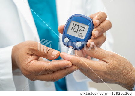 Doctor check diabetes from finger blood sugar level with finger lancet. Doctor check diabetes from finger blood sugar level with finger lancet. 129201206