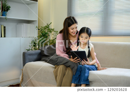 Mother and daughter using digital tablet together, enjoying online learning or entertainment 129201628