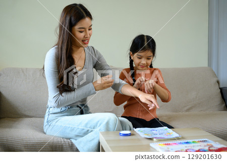 Mother teaching daughter skincare routine by applying moisturizing cream together at home Mother teaching daughter skincare routine by applying moisturizing cream together at home 129201630