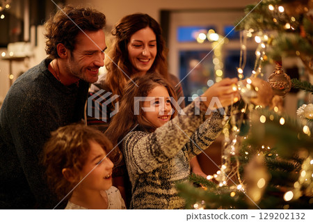 Happy family Christmas tree decorating lights smiling together holiday 129202132