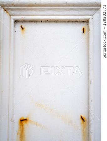 Rusty nails on a white wooden frame with peeling paint 129202573