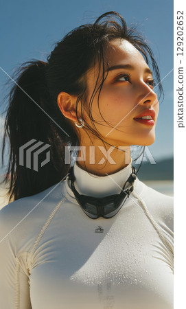 Young Korean woman enjoying a sunny beach day while wearing swimwear and a sporty accessory in a vibrant coastal setting 129202652