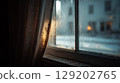 Close-up of a frosty window, water drops, and soft curtain light, winter home scene. 129202765