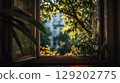 Sunlit open window looking out onto green trees, plants, and blurred building. Cozy home view. 129202775