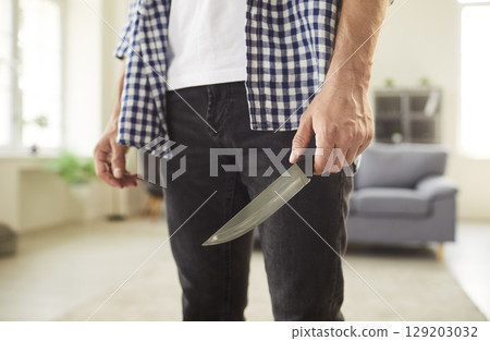 Man holding a kitchen knife in his hand illustrating the problem of domestic violence Man holding a kitchen knife in his hand illustrating the problem of domestic violence 129203032