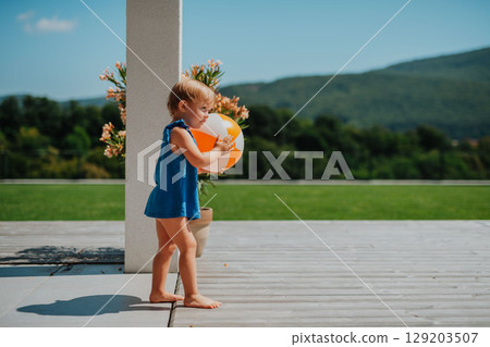 Little child enjoying outdoor playtime with inflatable ball 129203507