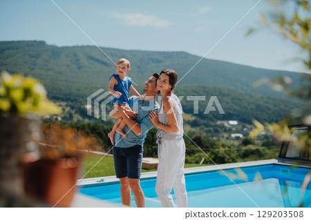 Happy parents playing with toddler girl on summer day outdoors 129203508