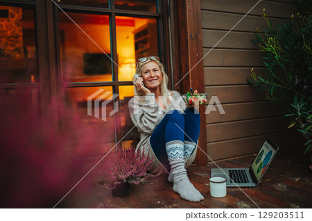 Elderly woman having dinner while working from homeoffice. Elderly woman having dinner while working from homeoffice. 129203511
