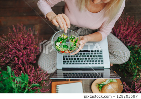 Top view of woman having lunch while working from homeoffice. 129203597