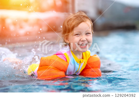 Happy child swimming with armbands in pool having fun Happy child swimming with armbands in pool having fun 129204392