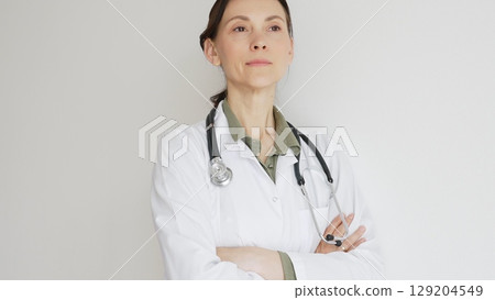 Portrait of a doctor woman medical professional in white lab coat, stethoscope draped, standing with crossed arms and displaying confident, authoritative healthcare demeanor. Medicine and health care Portrait of a doctor woman medical professional in white lab coat, stethoscope draped, standing with crossed arms and displaying confident, authoritative healthcare demeanor. Medicine and health care 129204549