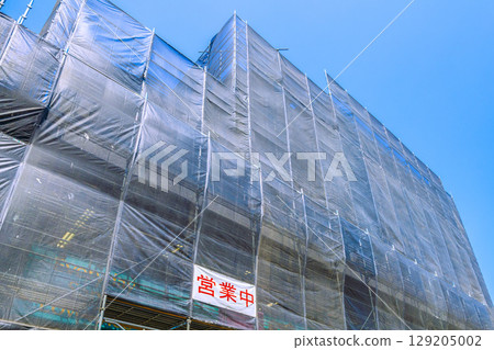 Yokohama cityscape in Japan. View of apartment building repairs and inspections, scaffolding, and protective netting. Open now... 129205002