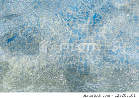 Light dances on the surface of the clear blue water, forming beautiful patterns that evoke tranquility. The vibrant colors create a refreshing atmosphere at the poolside Light dances on the surface of the clear blue water, forming beautiful patterns that evoke tranquility. The vibrant colors create a refreshing atmosphere at the poolside 129205101