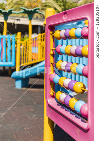 Brightly colored playground features a climbing structure and an abacus, providing a fun and educational environment for children enjoying outdoor play in a sunny setting 129205107