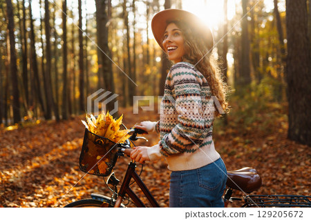 Happy active young woman on bike in autumn park at sunset. Concept of people, recreation, active lifestyle. 129205672