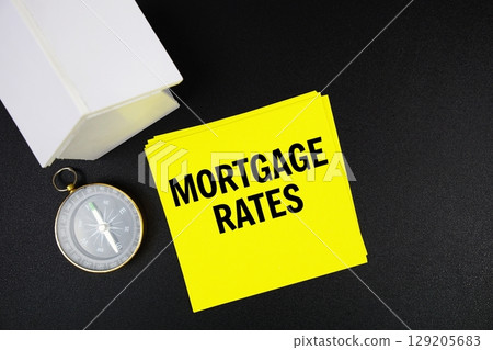 Mortgage Rates text message with white house model and magnifying glass top view on black background Mortgage Rates text message with white house model and magnifying glass top view on black background 129205683