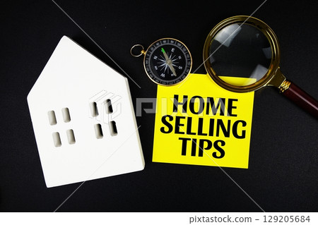Home Selling Tips text message with white house model and magnifying glass top view on black background Home Selling Tips text message with white house model and magnifying glass top view on black background 129205684