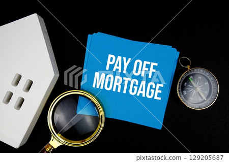 Pay Off Mortgage text message with white house model and magnifying glass top view on black background 129205687