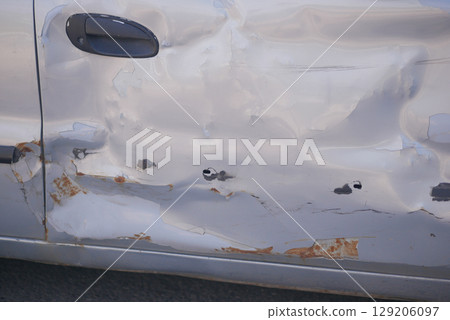 Car door with visible damage near a city street 129206097