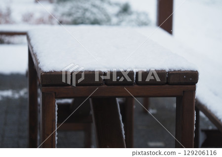 Snow covers a wooden outdoor table in winter setting 129206116