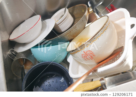 Dishes piled high in a kitchen sink after dinner cleanup 129206171
