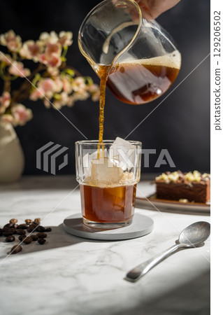 Pouring black coffee in a glass with iced Pouring black coffee in a glass with iced 129206502