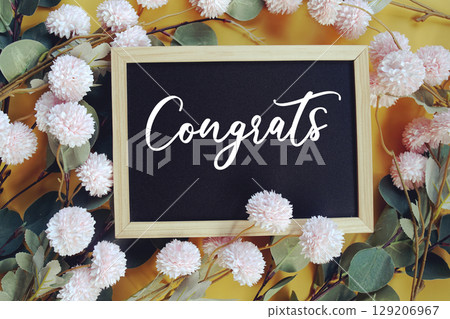 Congrats text with flowers decoration on yellow background 129206967