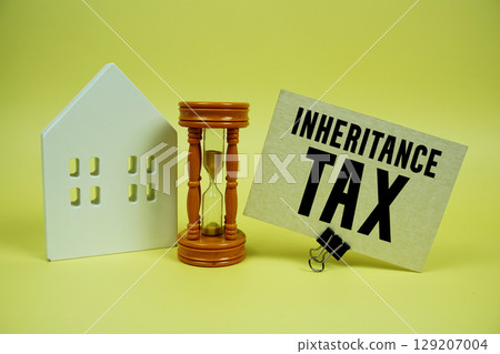 Inheritance Tax text with house model and hour glass background 129207004