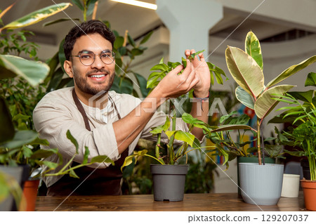 Young man working in the flower shop and looking involved Young man working in the flower shop and looking involved 129207037