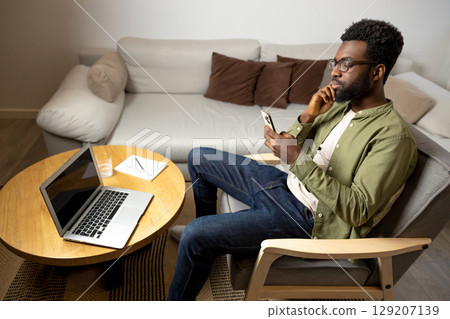 Top view of a young man sitting at the round table and working on laptop Top view of a young man sitting at the round table and working on laptop 129207139