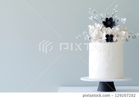 This sophisticated cake, adorned with subtle embossed textures and tasteful floral decorations, stands elegantly on a simple pedestal against a soft, muted backdrop, showcasing refined beauty 129207282