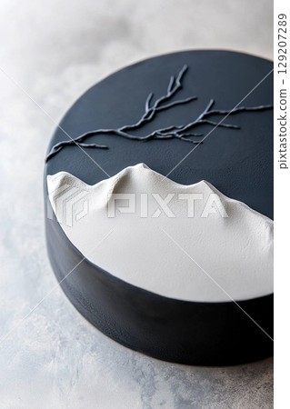 Smooth black and white cake showcases subtle embossed mountain details and delicate branches, perfect for celebrations. This design emphasizes elegance and sophistication at any gathering 129207289