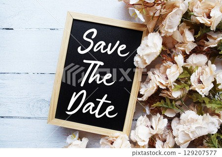 Save The Date text with flower decoration on wooden background 129207577