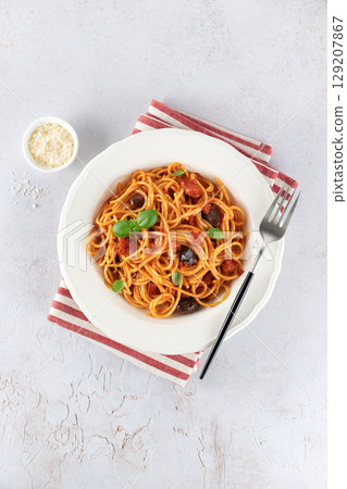 Spaghetti alla puttanesca or Neapolitan pasta with tomatoes, anchovies, olives on white background. 129207867