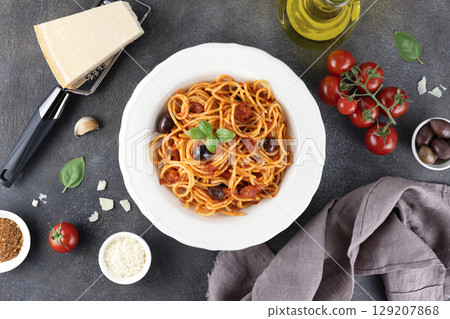 Spaghetti alla puttanesca or Neapolitan pasta on gray background. Italian Cuisine. Top view.  129207868