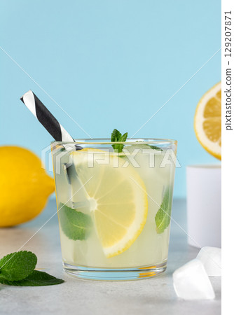 Glass of lemonade or mojito with lemon, mint on blue background close-up. Summer refreshing drinks. Glass of lemonade or mojito with lemon, mint on blue background close-up. Summer refreshing drinks. 129207871