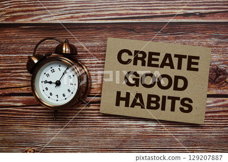 Create Good Habits text with alarm clock on wooden background 129207887