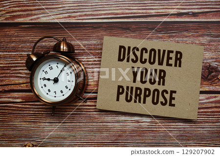 Discover Your Purpose text with alarm clock on wooden background 129207902
