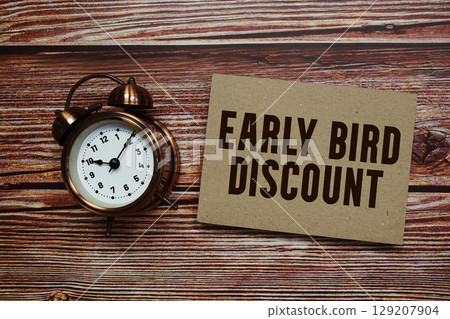 Early Bird Discount text with alarm clock on wooden background 129207904